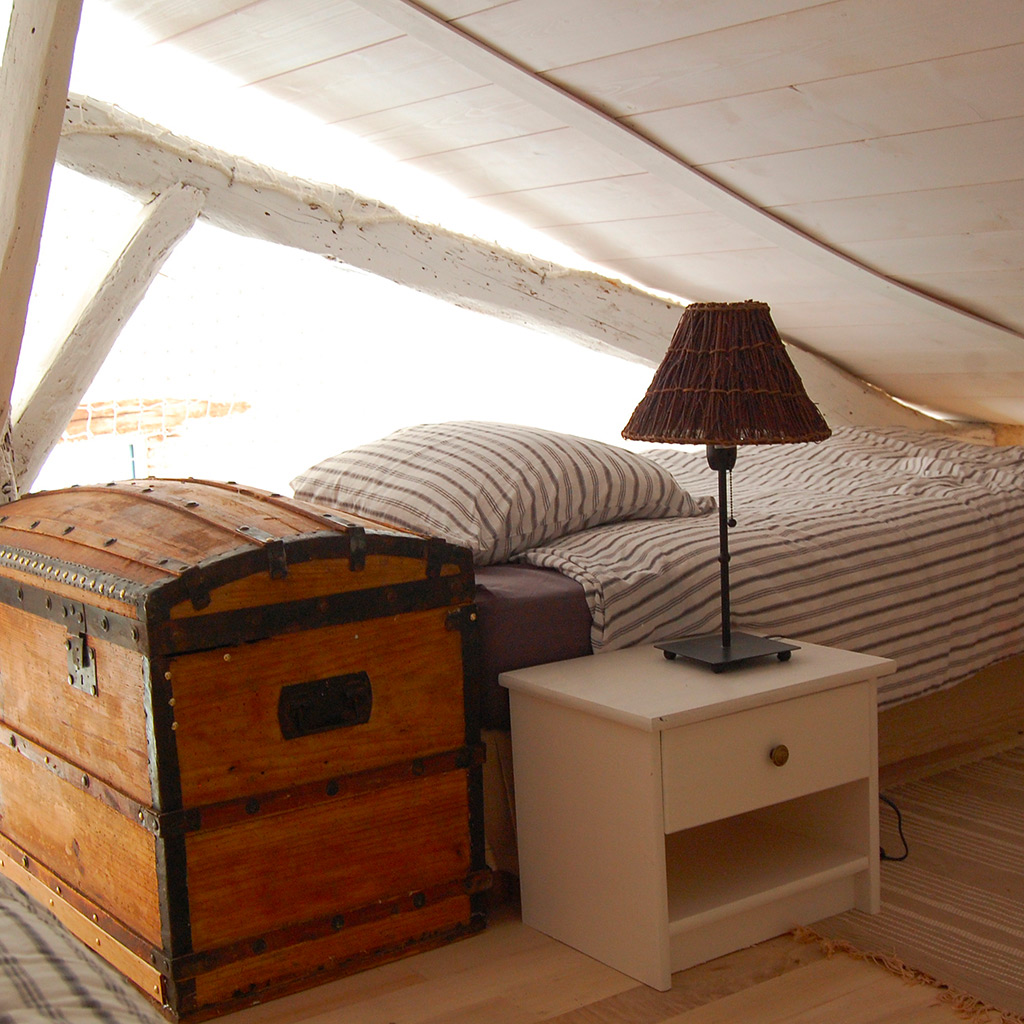 lit mezzanine sous comble poutre bois malle bois chevet Location gîte la Feuillade aux oiseaux à Laussou - Villeréal