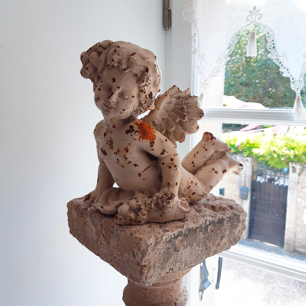 colonne pierre avec ange gravé devant fenêtre soleil Location gîte 7 au charme d'Antan à Beaumont du Périgord