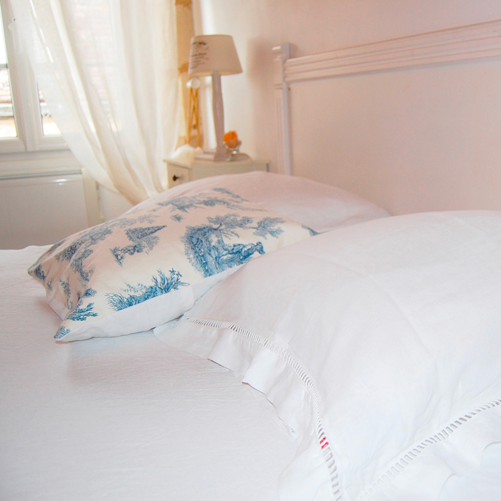 chambre avec lit en bois oreiller et linge de lit blanc et imprimé tapisserie bleu lumineuse location gîte 7 au charme d'Antan à Beaumont du Périgord